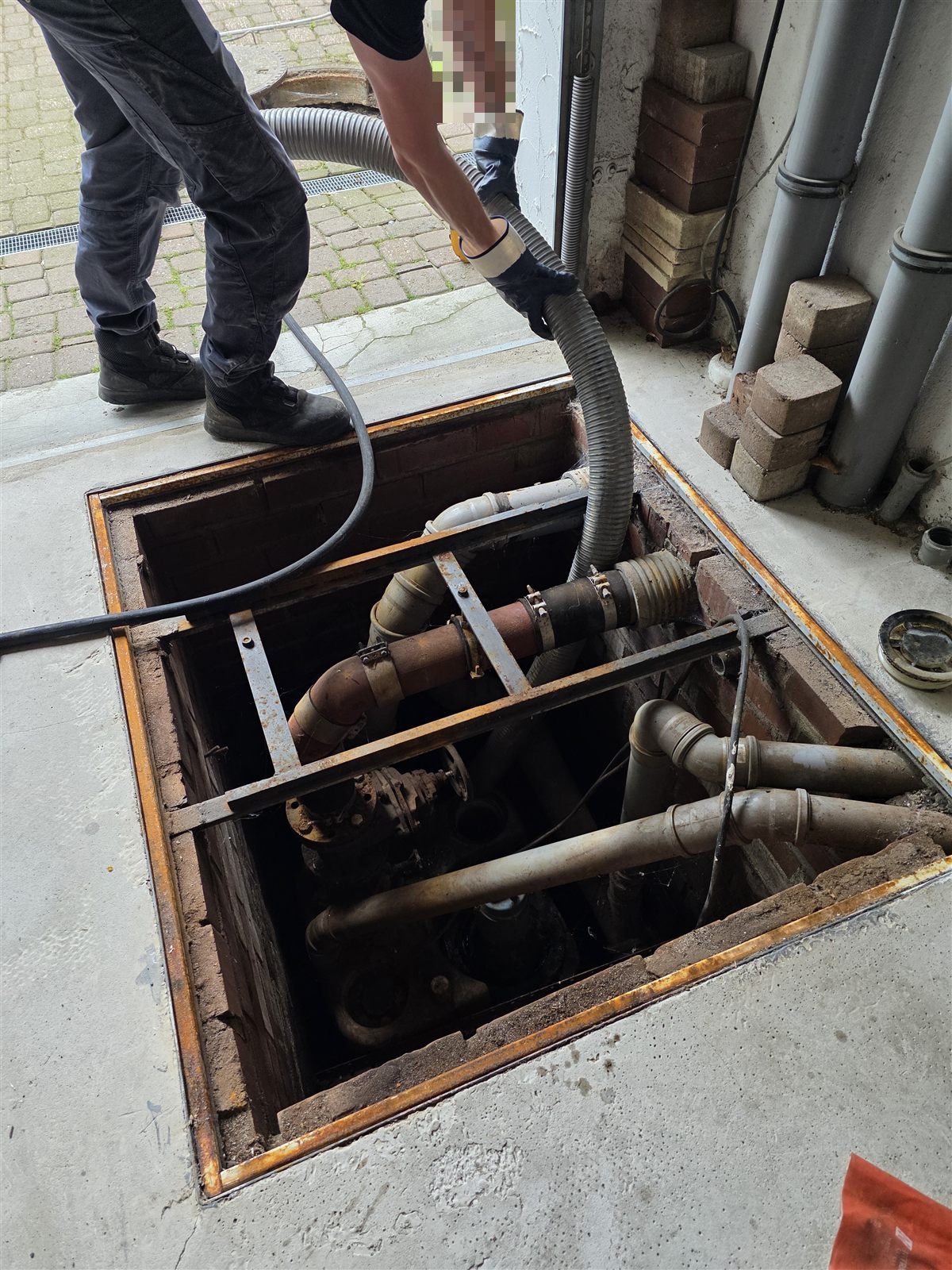 Servicetechniker pumpt den Pumpenschacht mit einem Saugschlauch leer